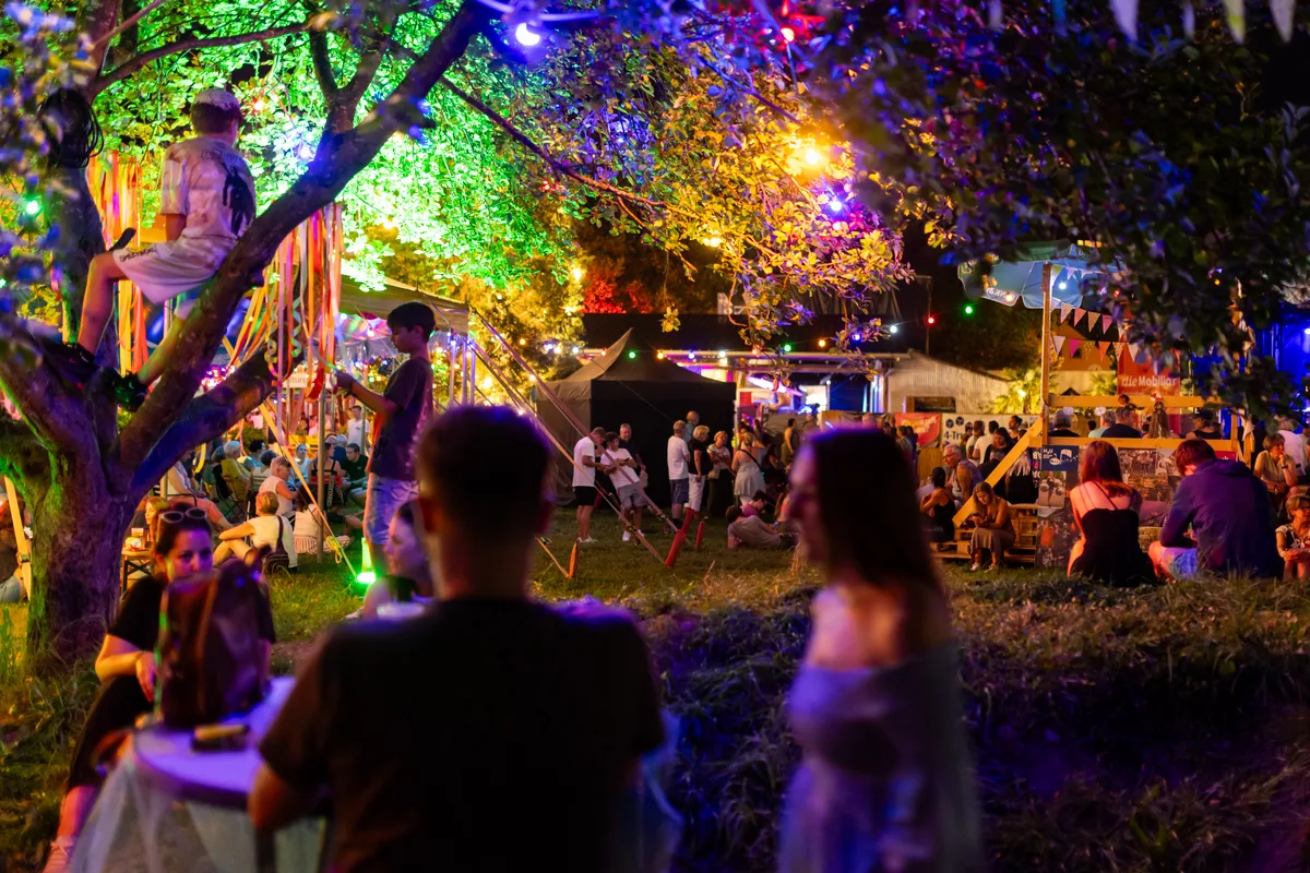 Kinder spielen auf einem farbig beleuchteten Festivalgelände.